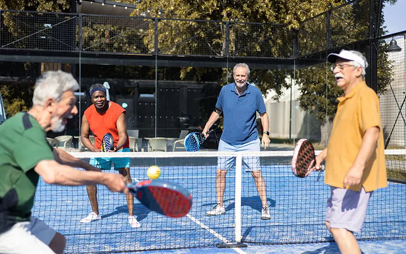 Four senior men playing padel in doubles