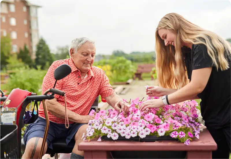 Senior man and younger woman tending to flowers outside