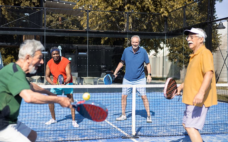Four senior men playing padel in doubles