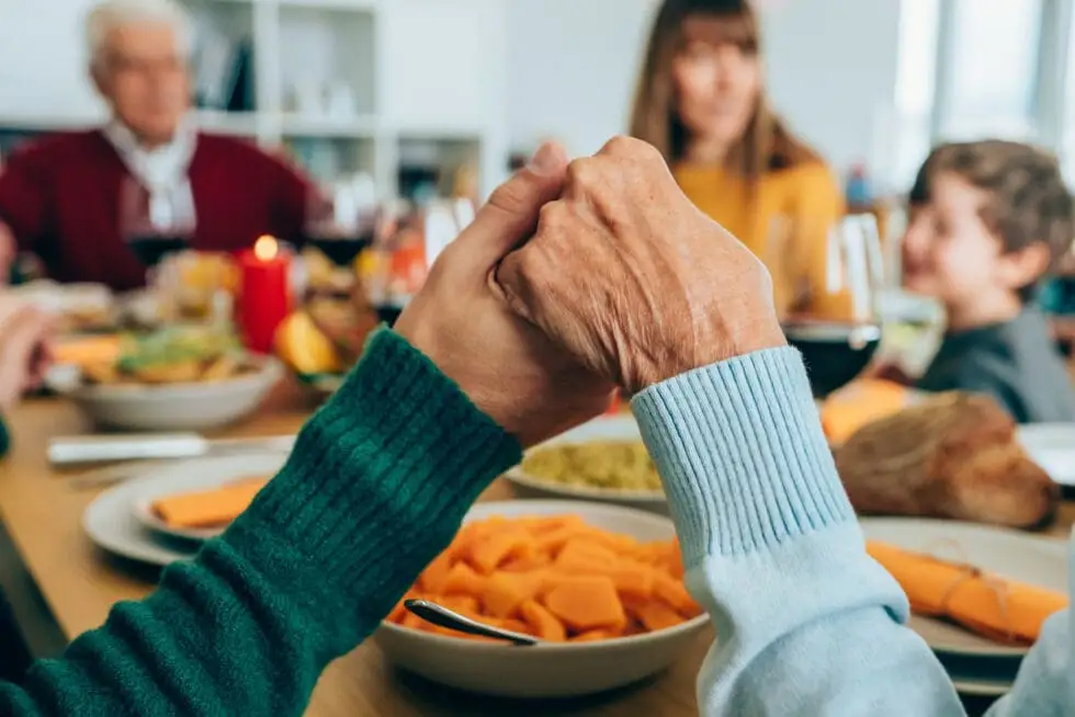 Two seniors holding hands at family holiday meal